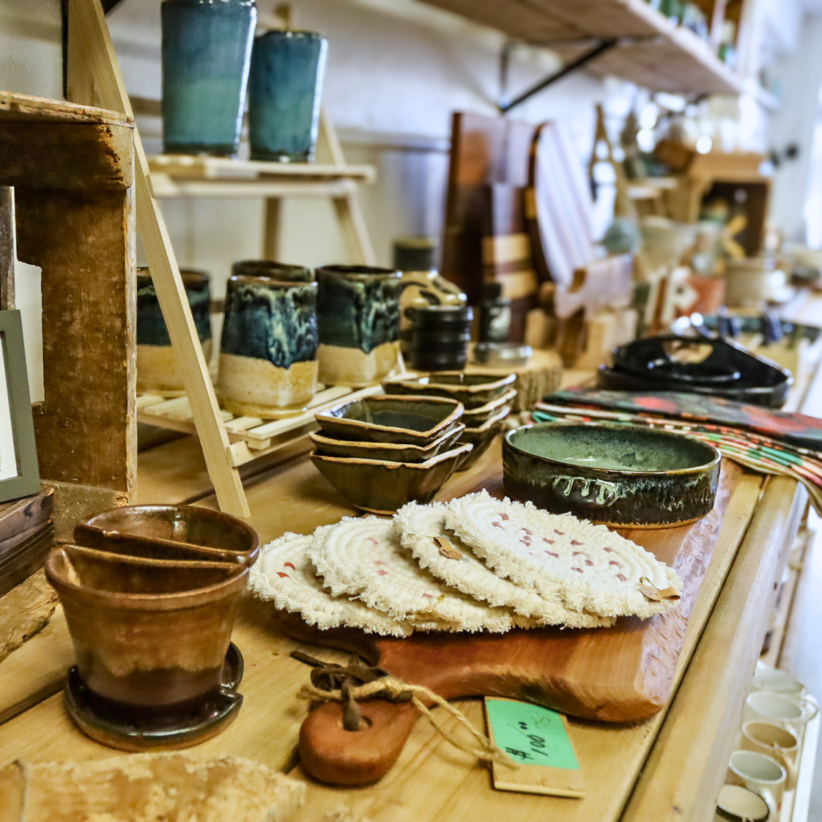Photo of a shelf with a variety of products including pottery, cutting board, woven coasters and more