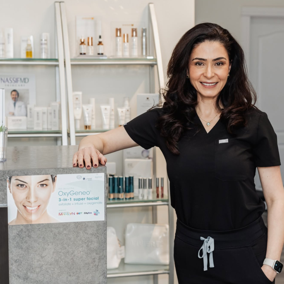 Owner of Micha's Medical Spa standing at the front counter with medical grade skin care in the background
