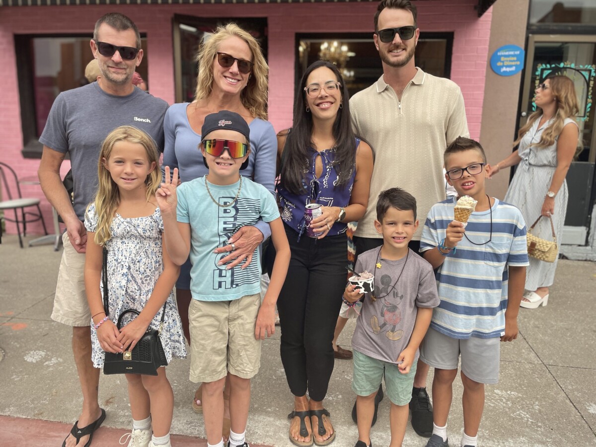 A family and friends enjoy gelato outside of a pink storefront