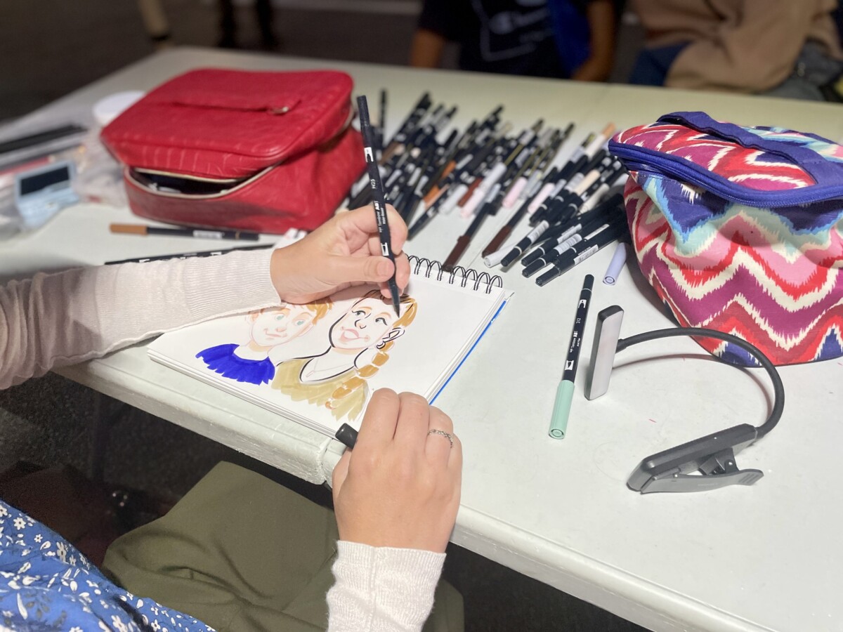 a caricature artist puts the finishing touches on a portrait of a mother and child